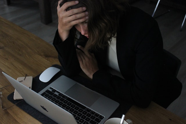 a woman experiencing stress while working on a laptop
