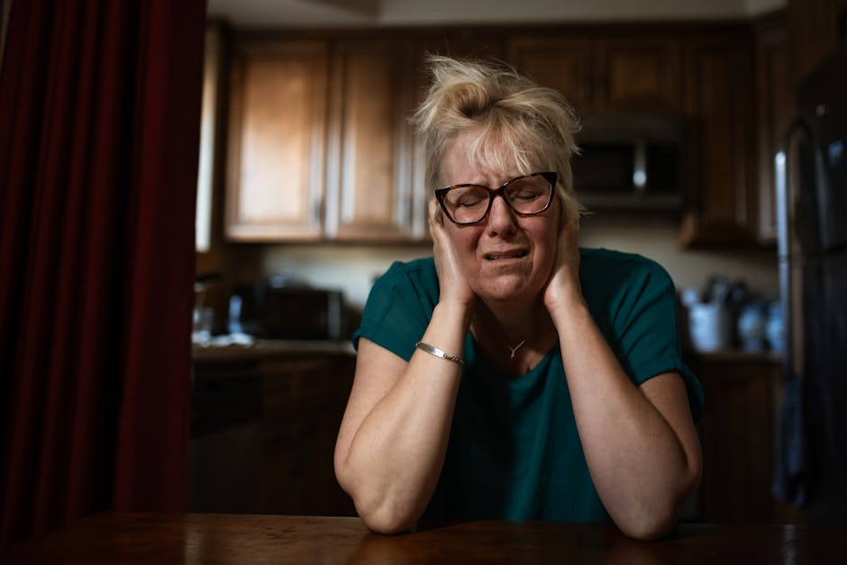 An adult woman in distress sitting at a table indoors, conveying past trauma.