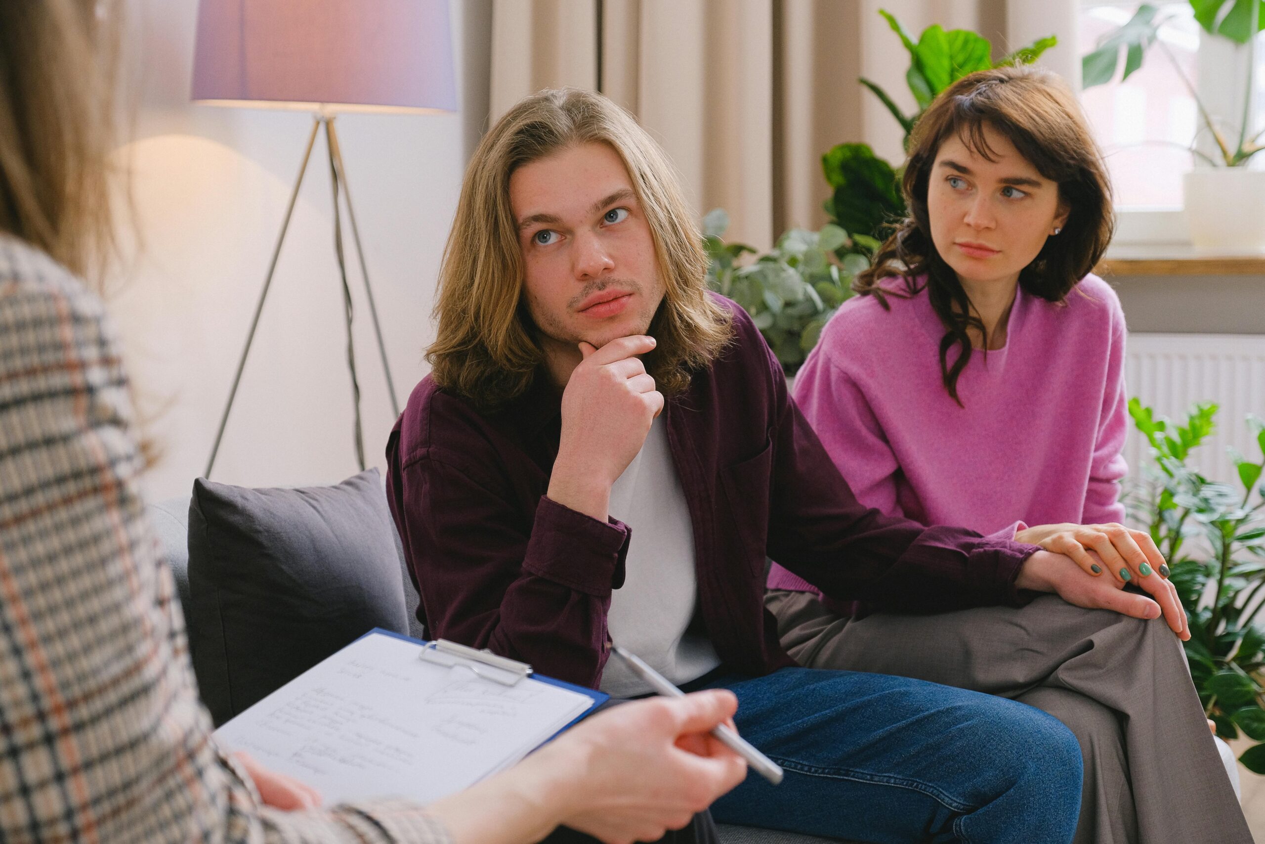 A couple holding hands during a therapy session in an office setting.