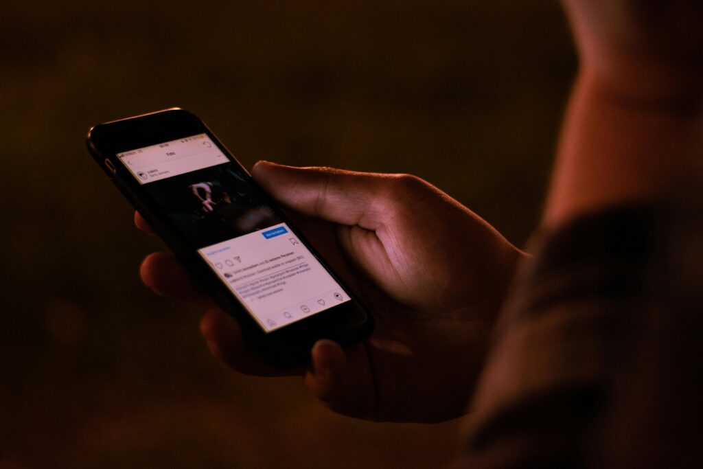 A person interacts with a smartphone in a dimly lit setting, emphasizing mobile technology usage.